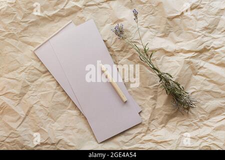 Composition de pose à plat avec un bloc-notes en papier kraft lacrymal, un crayon et de la lavande séchée sur un fond en papier kraft. Vue de dessus. Banque D'Images