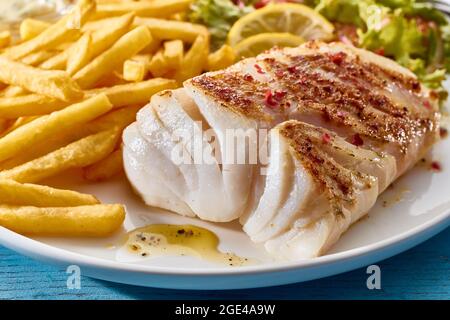 Gros plan d'un filet de poisson croustillant au four juteux servi avec des frites croustillantes et de la salade Banque D'Images