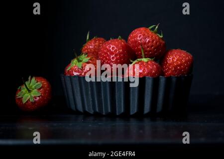 Des fraises rouges délicieuses et savoureuses dans un plat de flan cannelé en métal sur une table en bois sombre Banque D'Images