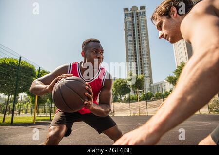 Joueur afro-américain concentré tenant le ballon de basket-ball près d'un ami pendant la compétition Banque D'Images