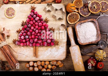 Repas de Noël. Ingrédients pour la cuisson de Noël: Sapin à base de canneberges congelées, ustensiles de cuisine et fruits secs sur une table en bois, Banque D'Images