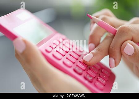 Femme d'affaires utilisant une calculatrice avec un stylo à la main calculant les dépenses financières Banque D'Images