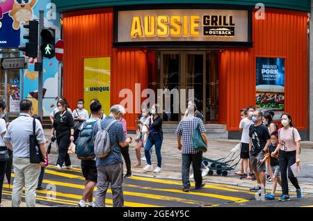 Hong Kong, Chine. 15 août 2021. Des piétons traversent la rue en face de la chaîne de restaurants décontractés américains de style australien, Outback Steakhouse, Aussie Grill, à Hong Kong. Crédit : SOPA Images Limited/Alamy Live News Banque D'Images