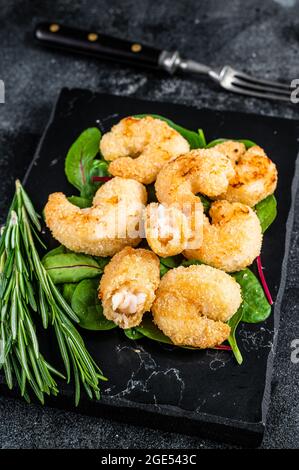 Crevettes croustillantes grillées sur un plateau en marbre avec salade verte. Arrière-plan noir. Vue de dessus Banque D'Images