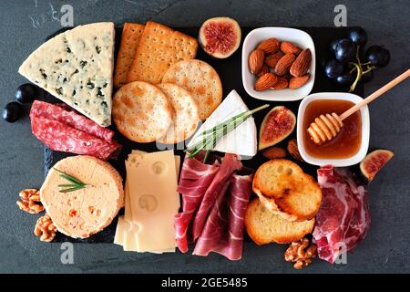 Plateau de fromages avec une sélection de fromages et de viandes. Vue de dessus sur un arrière-plan en ardoise sombre. Banque D'Images