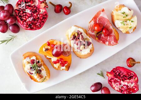Assortiment de hors-d'œuvre crostini avec une variété de garnitures. Au-dessus de la scène du tableau de vue sur un arrière-plan lumineux. Concept de fête alimentaire. Banque D'Images
