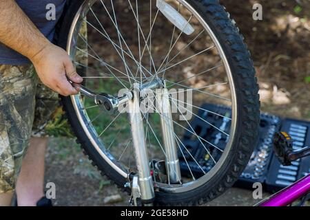 Homme répare des bicyclettes un beau mécanicien de vélo dans le processus de travail Banque D'Images