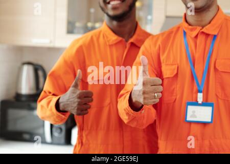 Équipe de plombiers professionnels montrant le pouce vers le haut après avoir terminé le travail dans la maison du client Banque D'Images