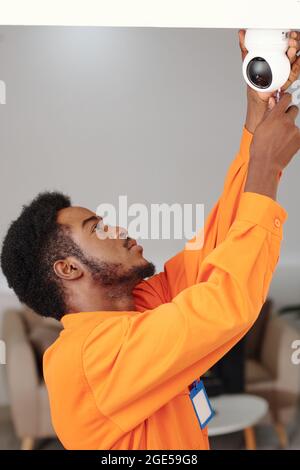 Un jeune technicien sérieux installe la caméra dans l'appartement du client Banque D'Images