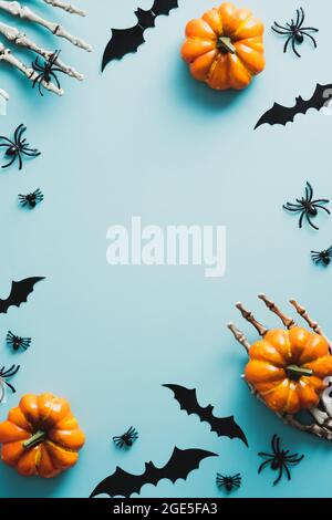 Joyeux Halloween concept de vacances. Cadre composé de citrouilles, mains de squelette, chauves-souris, araignées sur fond bleu. Flat lay, vue de dessus, au-dessus. Banque D'Images