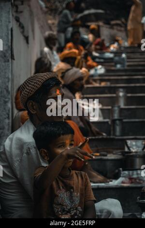 Photo de rue colorée d'un petit garçon mendiant enfant pointant son doigt vers inconnu pour montrer quelque chose à son père Banque D'Images