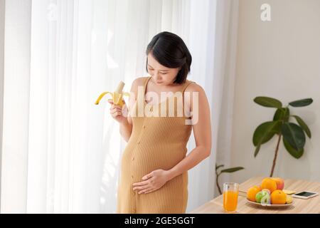 Femme mangeant de la banane. Bonne femme enceinte avec de la nourriture saine Banque D'Images