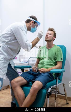 Médecin en vêtements de protection fait un test d'antigène sur un jeune homme, test de coronavirus, Covid-19, Kalymnos, Grèce Banque D'Images