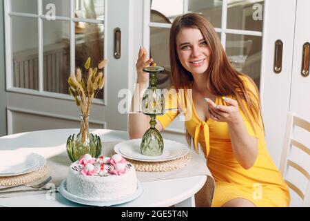 Jeune femme seule assise et ennuyeuse seule à la maison ou au café avec gâteau d'anniversaire blanc. Banque D'Images