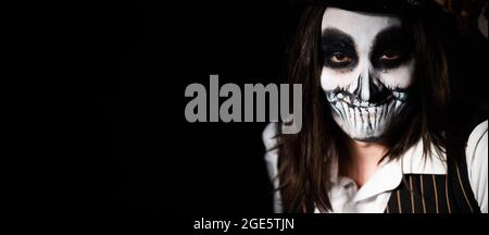 Jeune homme portant le maquillage du crâne dans l'obscurité. Costume de squelette d'Halloween Banque D'Images