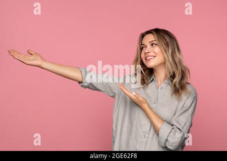 Bonne jeune fille point de côté tenant des palmiers ouverts présentant le produit, la publicité ou la vente au studio Banque D'Images