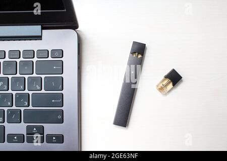 MOSCOU - 26 juin 2020 : bâton de vapeur de nicotine et ordinateur portable Juul e-cigarette. Banque D'Images