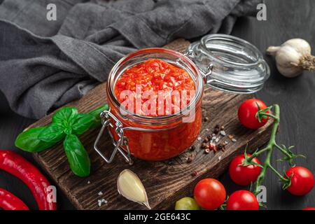 Sauce tomate dans un pot en verre sur le fond des ingrédients. Banque D'Images