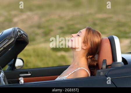 Profil d'une femme respirant de l'air frais dans une voiture convertible Banque D'Images