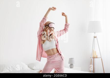 Le matin, réveillez-vous avec de la musique, profitez de la liberté, de la paix, de la musique, des vacances et du bonheur. Souriant jeune belle blonde femme en pyjama rose et dormir Banque D'Images