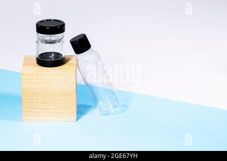 Bouteilles de voyage transparentes en plastique pour cosmétiques sur podium en bois : savon, gel, lotion, crème, shampooing, Maquillage et liquides sur fond bleu. Moderne Banque D'Images