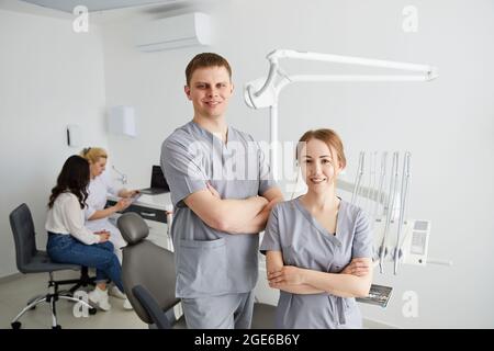Deux dentistes - un homme et une femme sont debout dans le bureau, et en arrière-plan se trouve un patient et un assistant Banque D'Images