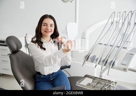 Femme heureuse patiente vérifiant les dents dans le miroir.