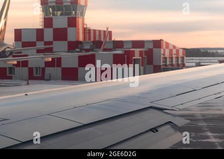 bâtiment de l'aéroport à l'aube sur la piste avec feu à éclats peint en carreaux rouges et blancs. vue sur la fenêtre de l'avion Banque D'Images