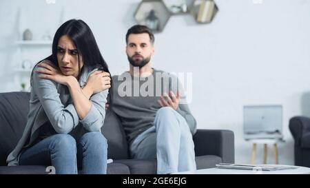 triste femme assise près d'un petit ami flou et mécontent Banque D'Images