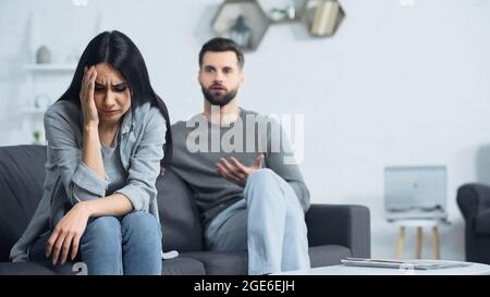 une femme contrariée assise près d'un petit ami flou et mécontent Banque D'Images