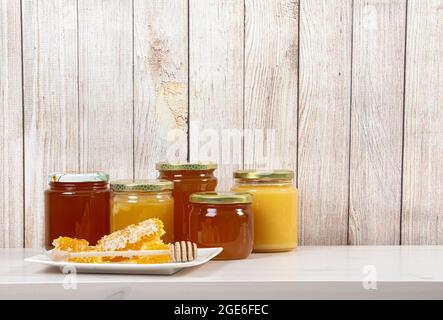 Divers pots de miel avec différentes couleurs miel, beaucoup d'espace de copie sur fond de bois clair. Concept de fond de bordure de miel. Banque D'Images