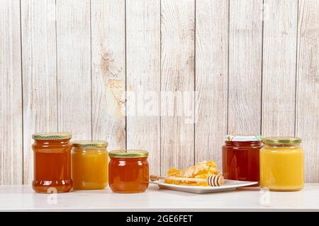 Divers pots de miel avec différentes couleurs miel, beaucoup d'espace de copie sur fond de bois clair. Concept de fond de bordure de miel. Banque D'Images