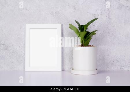 Maquette de cadre blanc vertical et plantes en pot sur table à la maison, maquette d'affiche pour la présentation sur bureau, votre conception pour la galerie photo et l'image Banque D'Images