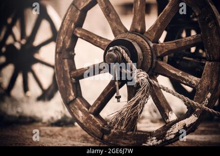 Roues en bois d'un ancien chariot debout dans la cour d'un village dans la campagne en soirée. Objets vintage du passé. Histoire. Banque D'Images