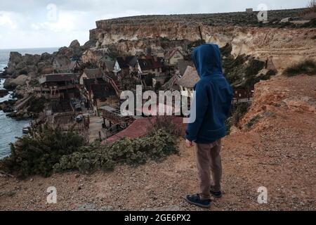 Un enfant avec un sweat à capuche est en train d'observer le village de Popeye (village de Sweethaven) à Malte d'en haut. Banque D'Images