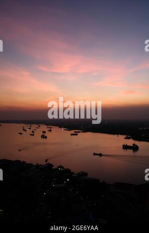 Vue aérienne de la rivière Chao Phraya et du quartier de la capitale du Samutprakan au crépuscule. Des nuages spectaculaires et un coucher de soleil haut en couleur se reflètent sur la rivière. Banque D'Images