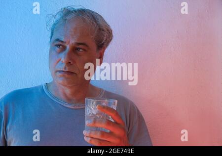 homme mature avec des lumières d'ambiance rouges et bleues sur fond blanc Banque D'Images