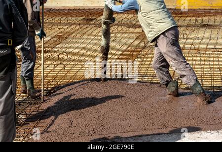 Les constructeurs travaillent sur le chantier de construction: Verser le béton brun pour la fondation Banque D'Images