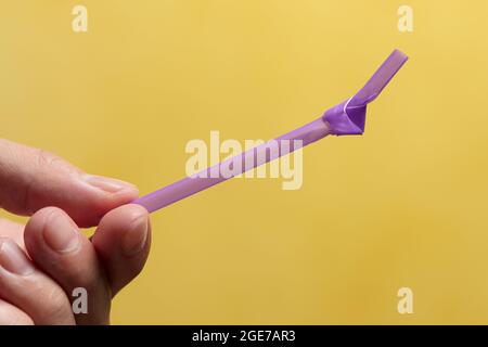 Main de l'homme tenant une paille avec un nœud dans elle. Concept plastique à usage unique Banque D'Images