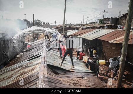 Nairobi, Kenya. 17 août 2021. Les habitants de la région s'aident les uns les autres à faire feu à Bombolulu Kibera, Nairobi. Le 17 août 2021, la plupart des résidents se sont réunis pour aider à mettre fin à un incendie qui s'est produit mardi après-midi à partir des fils électriques enchevêtrés qui alimentent différentes maisons. Le feu a rasé douze maisons et propriétés laissant la plupart des résidents sans nulle part pour se tourner vers la plupart des résidents sans emploi. (Credit image: © Donwilson Odhiambo/ZUMA Press Wire) Banque D'Images