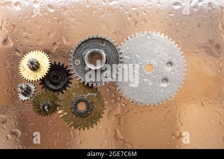 Assortiment de pignons métalliques sur verre, avec gouttes d'eau ou condensation, fond en bois Banque D'Images