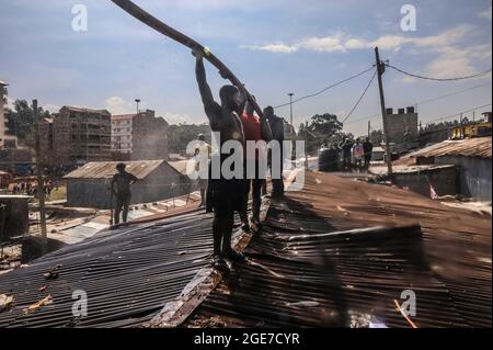 Nairobi, Kenya. 17 août 2021. Les résidents grimpent sur les toits pour aider à faire feu à Bombolulu Kibera, Nairobi. Le 17 août 2021, la plupart des résidents se sont réunis pour aider à mettre fin à un incendie qui s'est produit mardi après-midi à partir des fils électriques enchevêtrés qui alimentent différentes maisons. Le feu a rasé douze maisons et propriétés laissant la plupart des résidents sans nulle part pour se tourner vers la plupart des résidents sans emploi. (Credit image: © Donwilson Odhiambo/ZUMA Press Wire) Banque D'Images