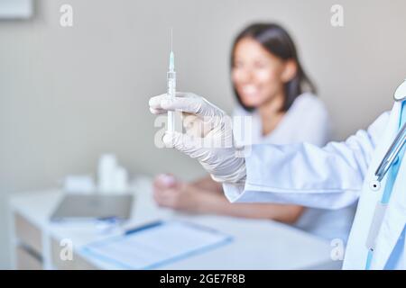 Médecin tenant une seringue avec le vaccin covid 19 coronavirus, prêt à vacciner la patiente africaine heureuse Banque D'Images