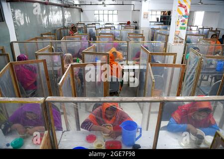 Dhaka, Bangladesh. 17 août 2021. Les employés de Ready-made Garment (RMG) dînent séparés par des feuilles de polyéthylène, comme mesure de sécurité pour réduire la propagation du coronavirus, à l'usine de vêtements civil Engineering Limited à Dhaka. Crédit : SOPA Images Limited/Alamy Live News Banque D'Images