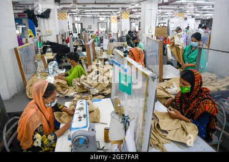 Dhaka, Bangladesh. 17 août 2021. Les employés de Ready-Made Garment (RMG) travaillent séparés par des feuilles de polyéthylène, comme mesure de sécurité pour réduire la propagation du coronavirus, à l'usine de vêtements civil Engineering Limited à Dhaka. Crédit : SOPA Images Limited/Alamy Live News Banque D'Images