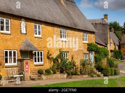 Royaume-Uni, Angleterre, Oxfordshire, Wroxton, main Street, Jolis cotswold en chaume autour du village vert Banque D'Images