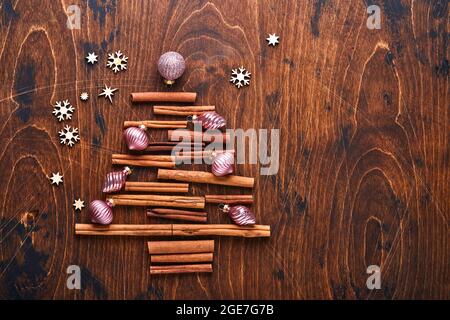 Sapin de Noël fait de cannelle en forme et d'épices anis avec des boules de Noël rouges et vertes sur fond de bois pour vos voeux de Noël. Vue de dessus Banque D'Images
