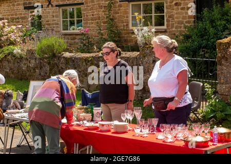 Royaume-Uni, Angleterre, Oxfordshire, Wroxton, fête annuelle de l'église en cours, villageois à bric a brac stall au bord du village vert Banque D'Images