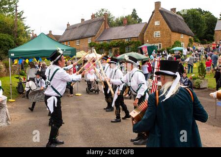 Royaume-Uni, Angleterre, Oxfordshire, Wroxton, fête annuelle de l'église en cours, Morris Dancers avec bâtons sur main Street, au bord du village vert Banque D'Images