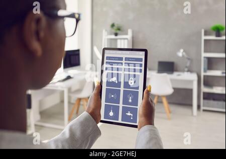 Femme tenant une tablette et utilisant une application moderne pour contrôler le système de sa Smart House Banque D'Images
